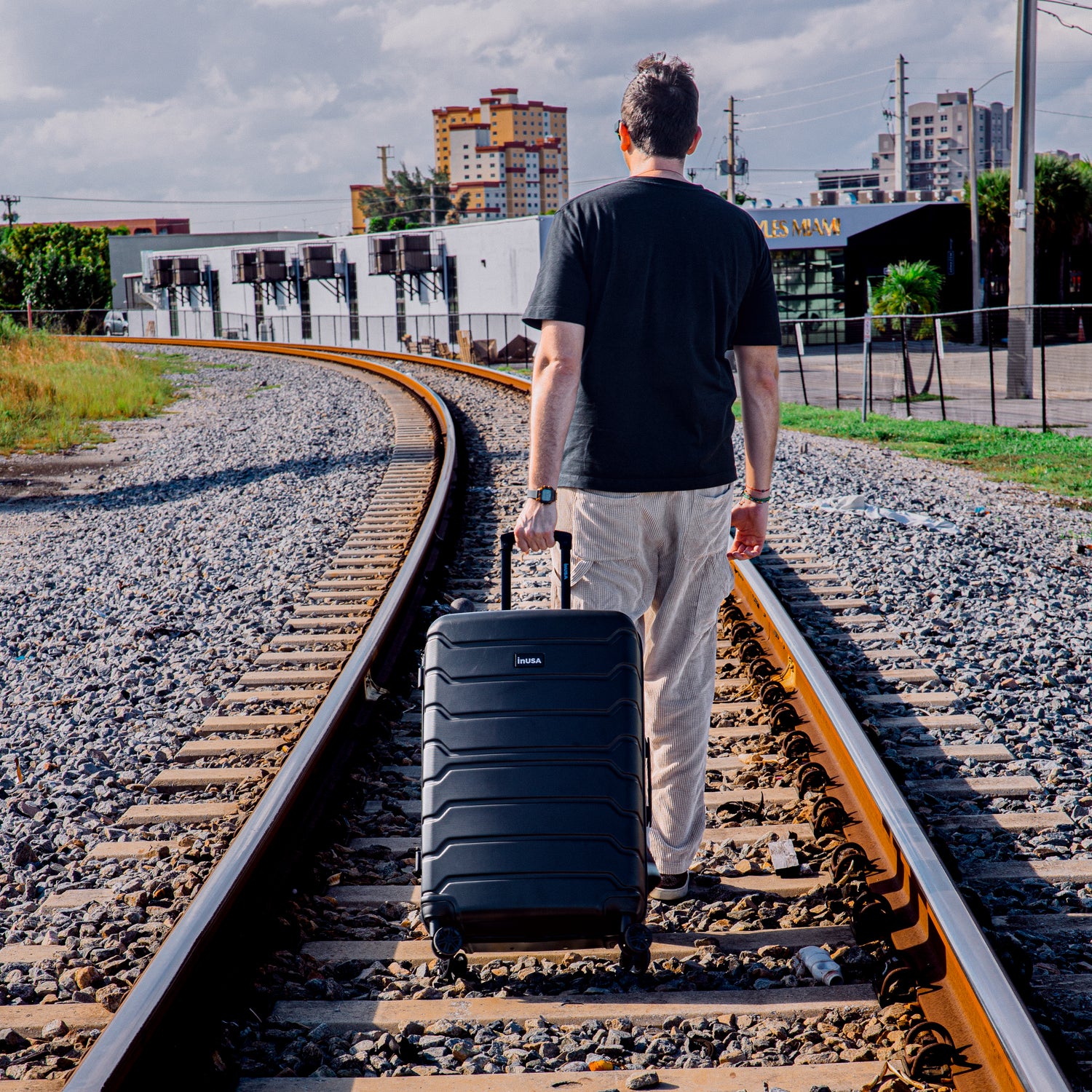 Man walking in the traintracks with Trend Black luggage